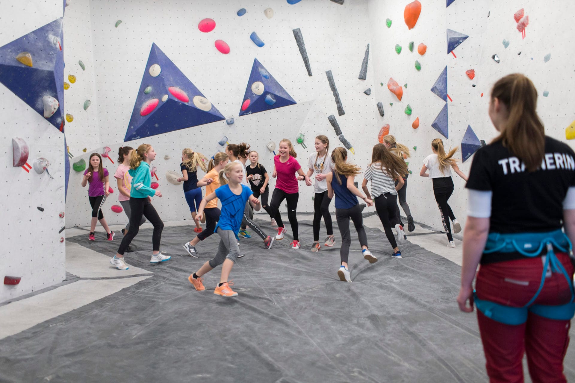 Kinder bewegen sich im Boulderbereich mit Trainerin