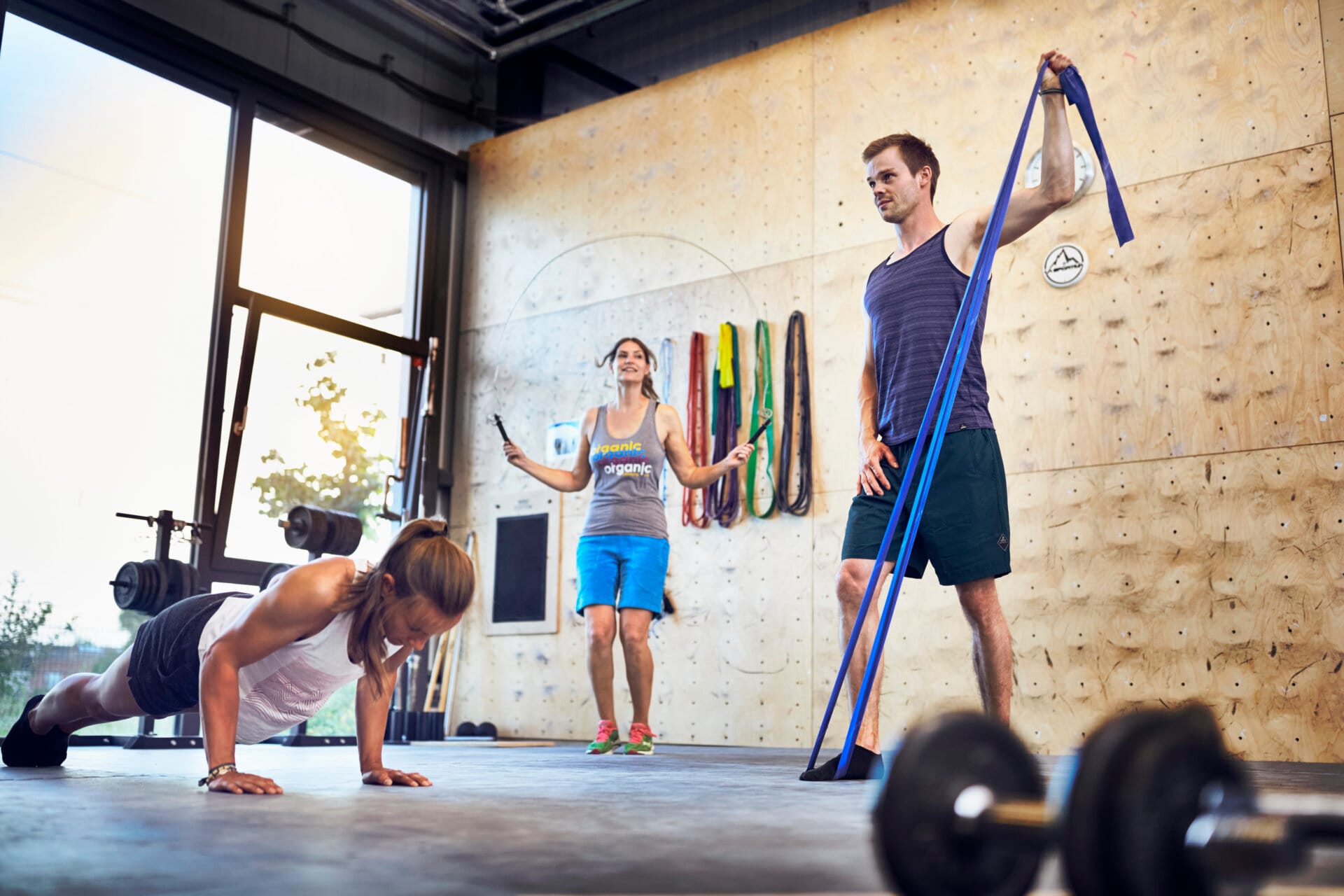 3 Personen im Trainingsraum (Liegestütze, Seilspringen, Terraband)
